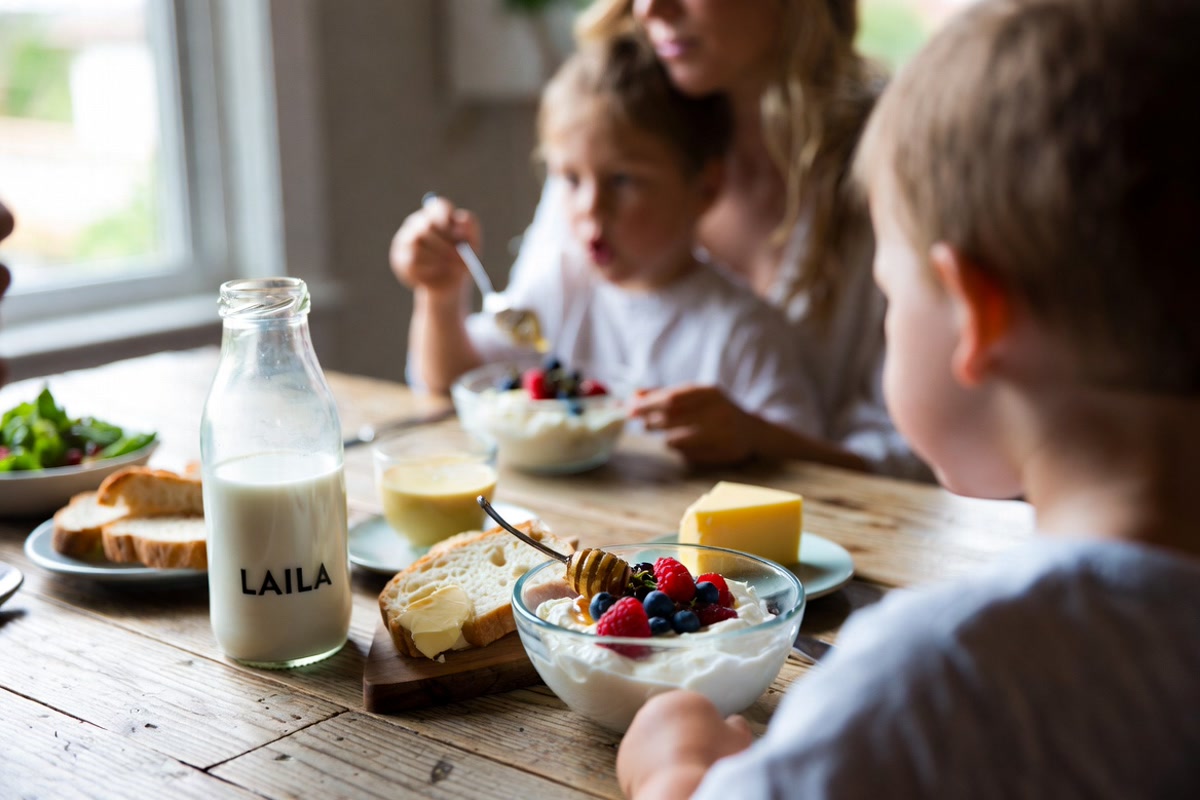 Family enjoying wholesome breakfast with LAILA Dairy products on a sunlit wooden table